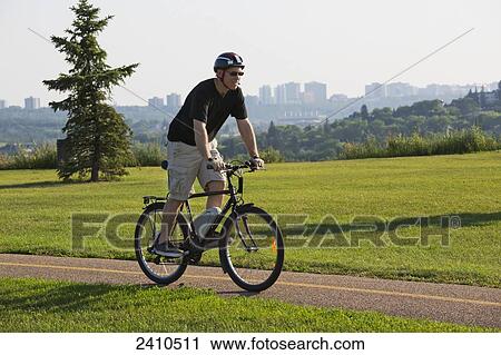 Man riding his electric bicycle with Edmonton city skyline in the background; Edmonton, Alberta, Canada View Large Photo Image Stock Image - Man riding his electric bicycle with Edmonton city skyline in the background; Edmonton, Alberta, Canada. Fotosearch