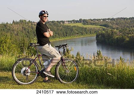 Man riding his electric bicycle with Edmonton city skyline in the background; Edmonton, Alberta, Canada View Large Photo Image Stock Photo - Man riding his electric bicycle with Edmonton city skyline in the background; Edmonton, Alberta, Canada. Fotosearch