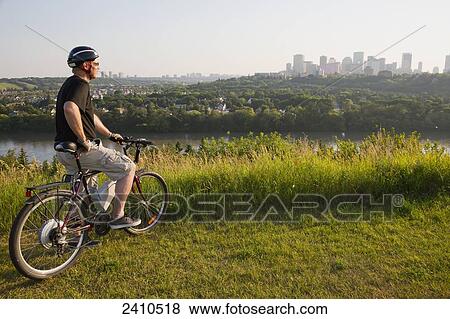 Man riding his electric bicycle with Edmonton city skyline in the background; Edmonton, Alberta, Canada View Large Photo Image Stock Photo - Man riding his electric bicycle with Edmonton city skyline in the background; Edmonton, Alberta, Canada. Fotosearch
