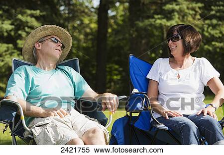 Stock Photography - Man sleeping in a park with his wife looking on; Edmonton, Alberta, Canada. Fotosearch