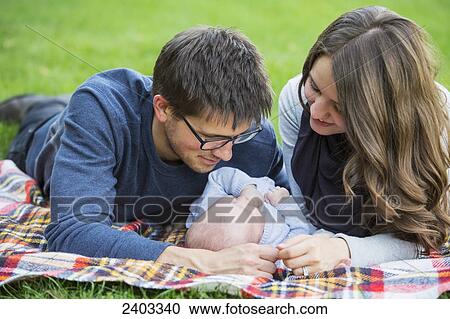 Stock Image - Married couple spending quality time with infant daughter in a park; Edmonton, Alberta, Canada. Fotosearch