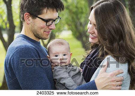 Stock Photography - Married couple with infant daughter in a park; Edmonton, Alberta, Canada. Fotosearch