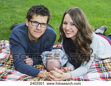 Stock Image - Married couple with their infant daughter in a park; Edmonton, Alberta, Canada. Fotosearch