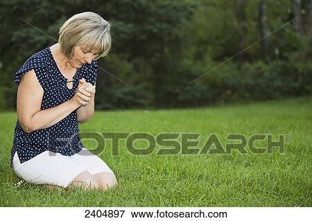 Mature woman praying in the park; Edmonton, Alberta, Canada View Large Photo Image Stock Photo - Mature woman praying in the park; Edmonton, Alberta, Canada. Fotosearch