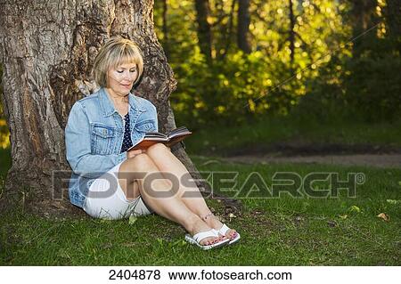 Mature woman reading a book in the park; Edmonton, Alberta, Canada View Large Photo Image Stock Photo - Mature woman reading a book in the park; Edmonton, Alberta, Canada. Fotosearch
