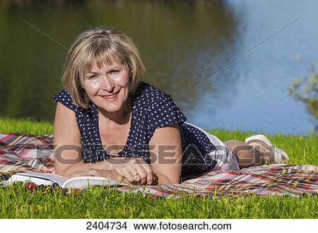 Mature woman relaxing and reading in Hawrelak Park; Edmonton, Alberta, Canada View Large Photo Image Picture - Mature woman relaxing and reading in Hawrelak Park; Edmonton, Alberta, Canada. Fotosearch