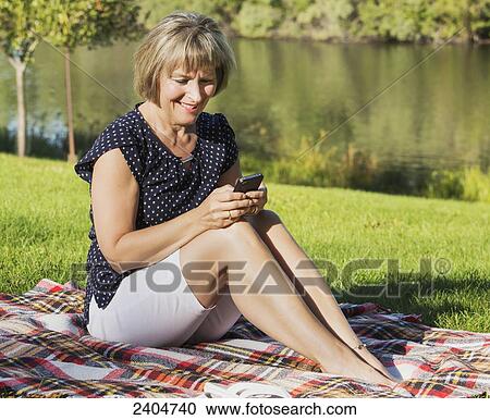 Mature woman using cell phone while relaxing in Hawrelak Park; Edmonton, Alberta, Canada View Large Photo Image Stock Image - Mature woman using cell phone while relaxing in Hawrelak Park; Edmonton, Alberta, Canada. Fotosearch