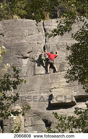 Stock Photo - Mid-Age Man Climbing With Daughter (Age 5) Up Granite Cliff At Stone Hills Near Rexford, Montana, Usa. Fotosearch