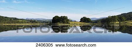 Mirror image of trees along a shoreline reflected in a tranquil lake; Lake District, Cumbria, England View Large Photo Image Stock Photography - Mirror image of trees along a shoreline reflected in a tranquil lake; Lake District, Cumbria, England. Fotosearch