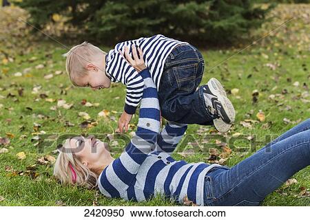 Mother holding her young son in the air in a park in autumn; Edmonton, Alberta, Canada View Large Photo Image Stock Image - Mother holding her young son in the air in a park in autumn; Edmonton, Alberta, Canada. Fotosearch