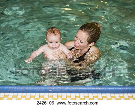 Mother teaching her infant to swim at an indoor pool; St. Albert, Alberta, Canada View Large Photo Image Stock Photograph - Mother teaching her infant to swim at an indoor pool; St. Albert, Alberta, Canada. Fotosearch