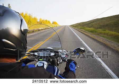 Stock Image - Motorcyclist riding on the highway, near Edmonton; Alberta, Canada. Fotosearch