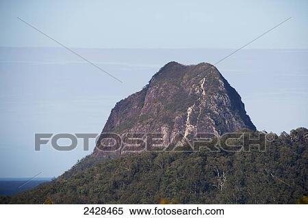Mountain peak rising up against a blue sky and cloud, Glass House mountains; Queensland, Australia View Large Photo Image Stock Photography - Mountain peak rising up against a blue sky and cloud, Glass House mountains; Queensland, Australia. Fotosearch