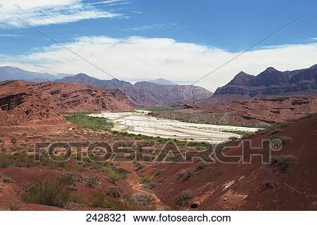 Stock Image - Mountainous landscape with red soil and rock in a valley; Valle de Lerma, Salta Province, Argentina. Fotosearch