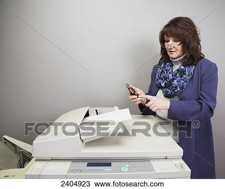 Office worker texting at a photocopy macine; Edmonton, Alberta, Canada View Large Photo Image Stock Image - Office worker texting at a photocopy macine; Edmonton, Alberta, Canada. Fotosearch