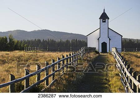 Stock Photo - Old wooden church in foothills with wooden fence and blue sky; Cochrane, Alberta, Canada. Fotosearch