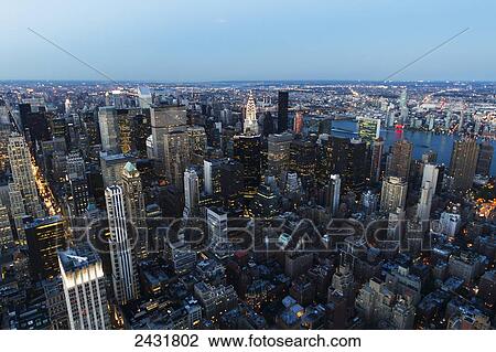 Stock Image - Panoramic view of the skyscrapers and the East River at dusk, as seen from the Empire State Building, New York City, New York, United States. Fotosearch