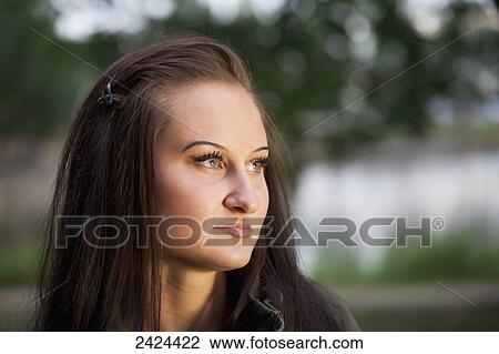 Stock Image - Portrait of a beautiful young woman in a park at twilight; St. Albert, Alberta, Canada. Fotosearch