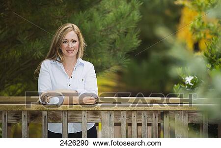 Stock Image - Portrait of a beautiful young woman on a bridge in a park; Langley, British Columbia, Canada. Fotosearch