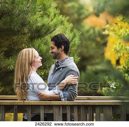Stock Image - Portrait of a couple embracing on a bridge in a park; Langley, British Columbia, Canada. Fotosearch
