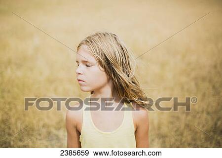 Stock Photo - Portrait of a girl in a golden field; Peachland, British Columbia, Canada. Fotosearch