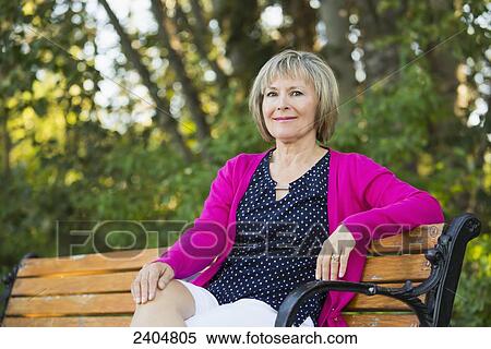 Stock Photography - Portrait of a mature woman sitting on a park bench; Edmonton, Alberta, Canada. Fotosearch