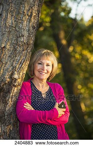 Portrait of a woman in a park holding her cell phone; Edmonton, Alberta, Canada View Large Photo Image Stock Image - Portrait of a woman in a park holding her cell phone; Edmonton, Alberta, Canada. Fotosearch