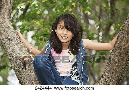 Portrait of a young girl sitting in a tree in a park; Edmonton, Alberta, Canada View Large Photo Image Picture - Portrait of a young girl sitting in a tree in a park; Edmonton, Alberta, Canada. Fotosearch