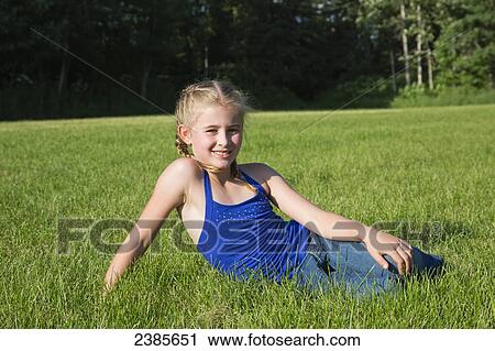 Stock Image - Portrait of a young girl sitting in the grass; Stony Plain, Alberta, Canada. Fotosearch