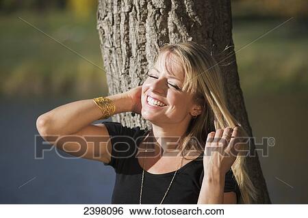 Stock Photograph - Portrait of a young woman smiling in a park; Edmonton, Alberta, Canada. Fotosearch