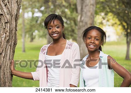 Stock Image - Portrait of two sisters in a park; Edmonton, Alberta, Canada. Fotosearch