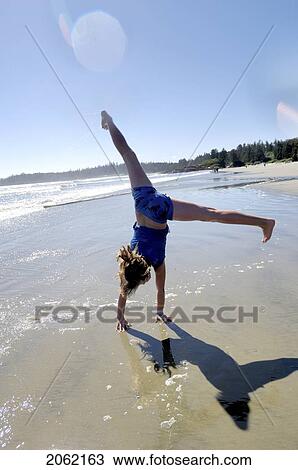 Stock Image - Pre-Teen Girl Performing Cartwheel On Beach, Vancouver Island, Canada. Fotosearch