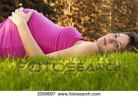 Pregnant Woman Lying Back On Grass, Manitoba, Canada View Large Photo Image Stock Photo - Pregnant Woman Lying Back On Grass, Manitoba, Canada. Fotosearch
