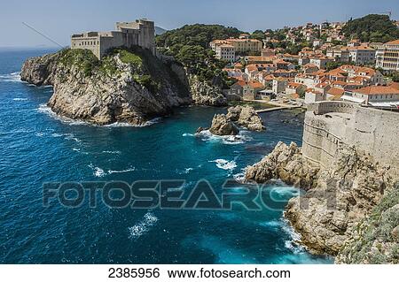 Stock Photograph - Rock cliffs and buildings along the coast; Dubrovnik, Dubrovnik-Neretva County, Croatia. Fotosearch