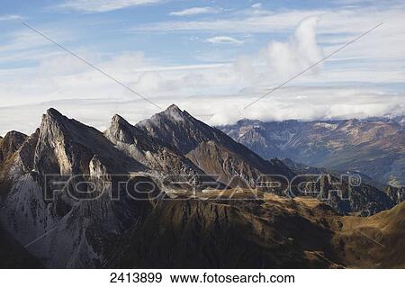 Rugged mountain peaks with clouds and blue sky; Hintertux, Austria View Large Photo Image Stock Photo - Rugged mountain peaks with clouds and blue sky; Hintertux, Austria. Fotosearch