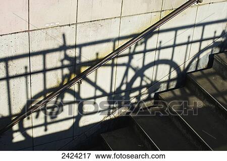 Stock Photo - Shadow of a railing and bicycle cast on a wall along steps; Paris, France. Fotosearch