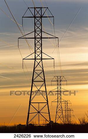 Silhouetted electric towers with wires at sunrise with orange cast clouds and blue sky; Calgary, Alberta, Canada View Large Photo Image Stock Photograph - Silhouetted electric towers with wires at sunrise with orange cast clouds and blue sky; Calgary, Alberta, Canada. Fotosearch