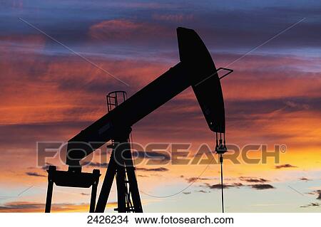 Picture - Silhouetted pumpjack at sunset with colourful clouds; Alberta, Canada. Fotosearch