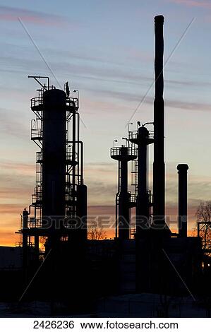 Silhouetted towers of a gas plant at sunset with orange cast clouds and blue sky; Bowden, Alberta, Canada View Large Photo Image Stock Photograph - Silhouetted towers of a gas plant at sunset with orange cast clouds and blue sky; Bowden, Alberta, Canada. Fotosearch