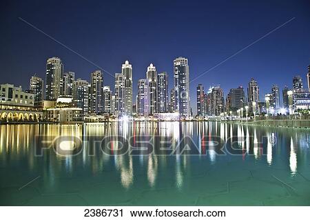 Stock Image - Skyline of Dubai and the buildings reflected in tranquil water; Dubai, United Arab Emirates. Fotosearch