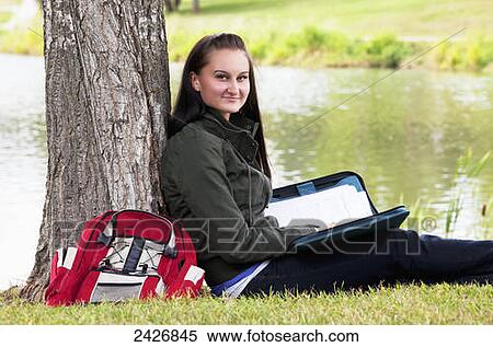 Stock Photography - Student studying outdoors beside a lake; St. Albert, Alberta, Canada. Fotosearch