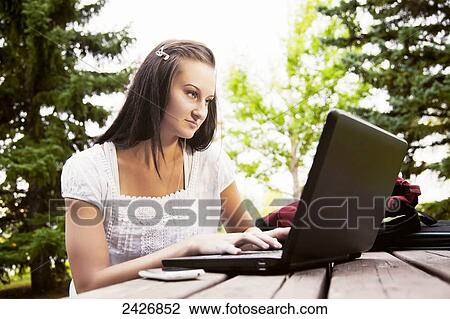 Stock Image - Student working on laptop outdoors in a park; St. Albert, Alberta, Canada. Fotosearch