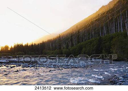 Stock Image - Sun setting over Hoh River below Hoh Burn; Washington, United States of America. Fotosearch
