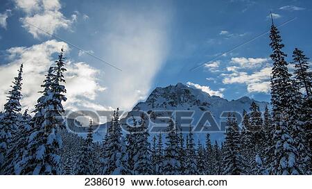 Sunlight illuminates clouds over a snowy mountain peak in winter; Pemberton, British Columbia, Canada View Large Photo Image Stock Photo - Sunlight illuminates clouds over a snowy mountain peak in winter; Pemberton, British Columbia, Canada. Fotosearch
