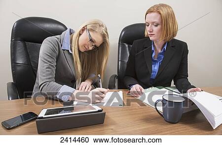 Stock Image - Supervisor and intern working together on an accounting project; Edmonton, Alberta, Canada. Fotosearch
