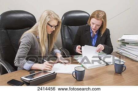 Stock Image - Supervisor and intern working together on an accounting project; Edmonton, Alberta, Canada. Fotosearch - Search Stock Photography, Poster Photos, Pictures, and Photo Clip Art
