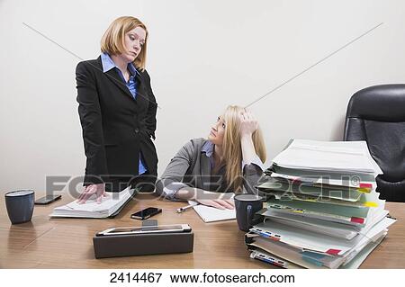 Stock Photo - Supervisor scowling at employee over lack of work accomplishment; Edmonton, Alberta, Canada. Fotosearch