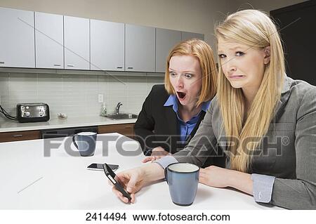 Supervisor shocked at messages on co-worker's smart phone; Edmonton, Alberta, Canada View Large Photo Image Picture - Supervisor shocked at messages on co-worker's smart phone; Edmonton, Alberta, Canada. Fotosearch