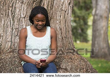 Teenage girl using a smart phone in a park; Edmonton, Alberta, Canada View Large Photo Image Stock Image - Teenage girl using a smart phone in a park; Edmonton, Alberta, Canada. Fotosearch