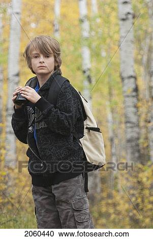 Stock Image - Ten Year Old Boy Holding Binoculars Wearing Hemp Backpack, Lake Katherine, Riding Mountain National Park, Manitoba. Fotosearch